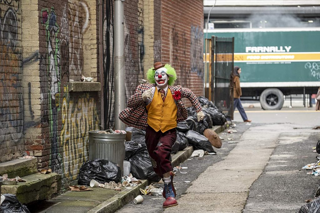 Joker interpretado por Joaquin Phoenix corriendo en un callejón de Gotham City